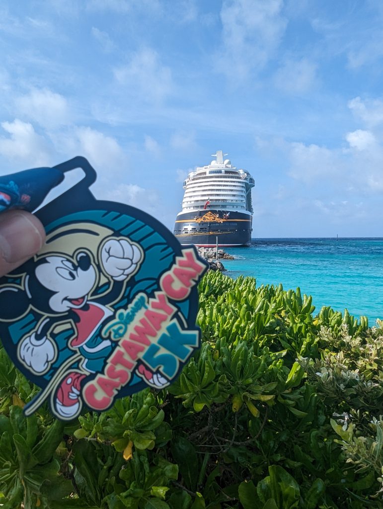Castaway Cay 5K medal, with Disney Dream in the background